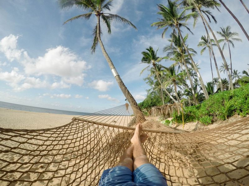Človek na sieťke nad zemou s výhľadom na palmy