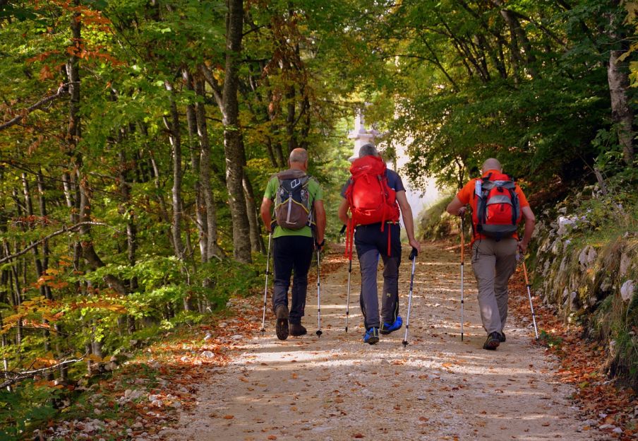 Traja muži s bahohmi kráčajú turistickým chodníkom